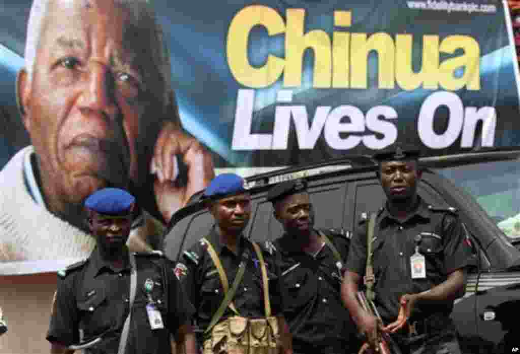 Police officers stand guards under a giant poster of late author Chinua Achebe, as part of an event in Awka, Nigeria, Wednesday, May 22, 2013.