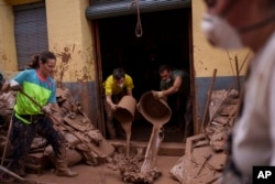 People clean mud from a house affected by floods, in Algemesi, Spain, Nov. 3, 2024.