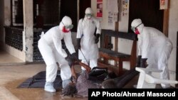 Petugas kesehatan berpakaian pelindung memindahkan seseorang yang dicurigai meninggal karena Ebola di Monrovia, Liberia (16/9). (AP/Abbas Dulleh)