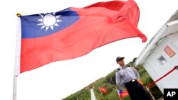 FILE - A Taiwan Coast Guard officer stands guard under a Taiwanese flag in the East China Sea, north of Taiwan, April 9, 2016.