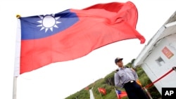 FILE - A Taiwan Coast Guard officer stands guard under a Taiwanese flag in the East China Sea, north of Taiwan, April 9, 2016.