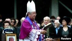 FILE - Poland's then-chief military chaplain Slawoj Leszek Glodz presides over a funeral in Warsaw, June 19, 2004. 