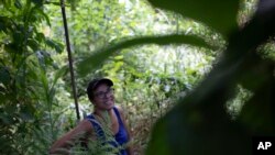 In this Jan. 6, 2020 photo, activist Ale Roque smiles as she sees a tree bearing fruit at her home in Rio's first favela, Morro da Providencia, Rio de Janeiro, Brazil. 
