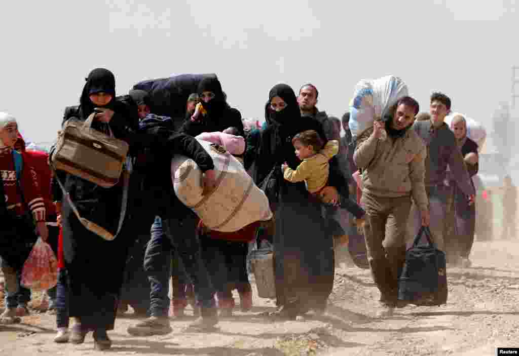 People flee the rebel-held town of Hammouriyeh, in the village of Beit Sawa, eastern Ghouta, Syria, March 15, 2018.