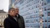 Japan's Foreign Minister Takeshi Iwaya, left, and Ukraine's Foreign Minister Andriiy Sybiha look at photos of fallen soldiers after a flower laying ceremony at the memorial wall in Kyiv, Ukraine, Nov. 16, 2024.