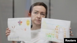 Alsu Kurmasheva, a Russian-American journalist for Radio Free Europe/Radio Liberty who is in custody after she was accused of violating Russia's law on foreign agents, holds drawings from her supporters as she attends a court hearing in Kazan, Russia, on May 31, 2024.