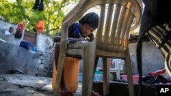 Christina Julien does her homework on a chair in Port-au-Prince, Haiti, Jan. 22, 2023.