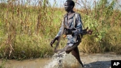 A rebel soldier patrols a flooded area near the town of Bentiu, South Sudan Saturday, Sept. 20, 2014.