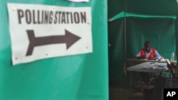 FILE - An election agent waits for people to cast their votes at a polling station on election day in Lusaka, Jan, 20, 2015.