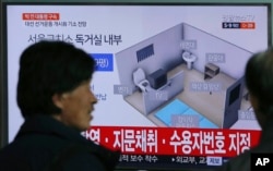 FILE - People watch a TV screen showing an image of solitary cell of Seoul Detention Center used by former South Korean President Park Geun-hye during a news program at the Seoul Railway Station in Seoul, South Korea, March 31, 2017.