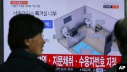 People watch a TV screen showing an image of solitary cell of Seoul Detention Center used by former South Korean President Park Geun-hye during a news program at the Seoul Railway Station in Seoul, South Korea, March 31, 2017.