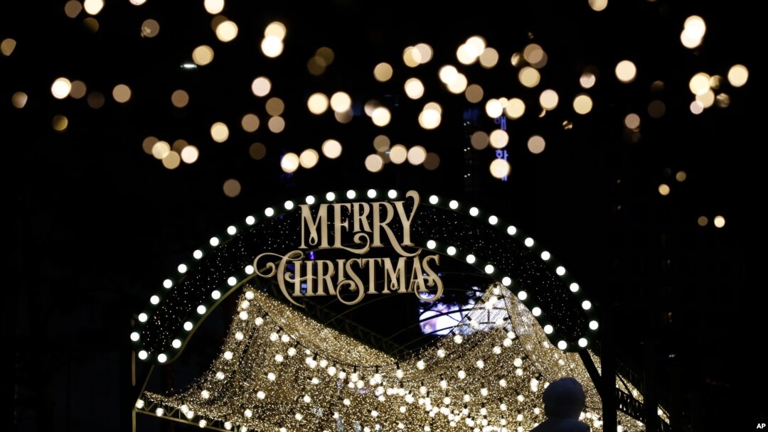 A woman wearing a face mask as a precaution against the coronavirus takes a photo near a Christmas decoration in Seoul, South Korea, Dec. 24, 2020.