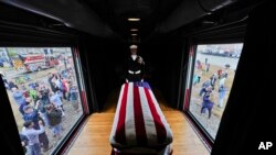 Peti jenazah mendiang Presiden George H.W. Bush berselimut bendera Amerika Serikat, dijaga oleh seorang petugas, dalam gerbong kereta bernomor 4141 rute Spring-College Station, melewati kawasan Magnolia, Texas, Texas, Kamis, 6 Desember 2018. 