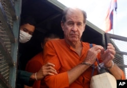 Australian filmmaker James Ricketson, right, is helped off a prisoner truck upon his arrival at Phnom Penh Municipal Court in Phnom Penh, Cambodia, Aug. 29, 2018.