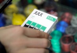 FILE - A woman buys refills for her Juul at a smoke shop in New York, Dec. 20, 2018.
