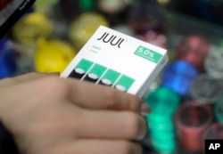 FILE - A woman buys refills for her Juul at a smoke shop in New York, Dec. 20, 2018.