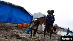 A boy carries a girl as they walk through the mud in an internally displaced persons (IDP) camp inside the U.N. base in Malakal, South Sudan, July 24, 2014.