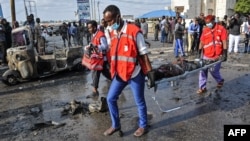 Des agents de la Croix-Rouge portent le corps d'une victime de l'explosion d'une voiture piégée à Modadishu, le 25 mars 2018. 