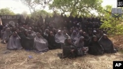 FILE - In this photo taken from video by Nigeria's Boko Haram terrorist network, Monday May 12, 2014 shows the alleged missing girls abducted from the northeastern town of Chibok. The new video purports to show dozens of abducted schoolgirls, covered in jihab and praying in Arabic. 