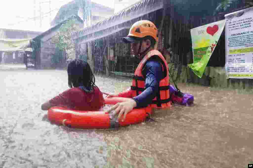 A rescuer assists a girl as they wade through flooding caused by Typhoon Rai in Cagayan de Oro City, southern Philippines, in this handout photo provided by the Philippine Coast Guard.