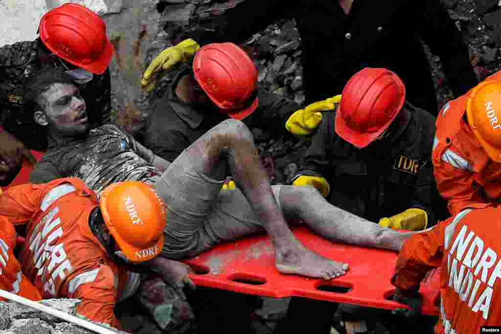 Members of the National Disaster Response Force (NDRF) rescue a man from the remains of a three-level residential building that collapsed in Bhiwandi on the outskirts of Mumbai, India.
