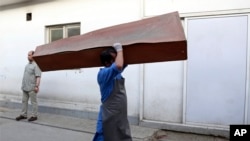 FILE - An Afghan man carries an empty casket in Kabul, Afghanistan, Sunday, July 15, 2018. Afghanistan has faced intense attacks by both the Taliban and the country's Islamic State affiliate recently.