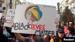 Des membres de groupes de défense des droits portent une bannière sur laquelle on peut lire "Les vies noires comptent" lors d'une manifestation à Tunis, en Tunisie, le 25 février 2023.