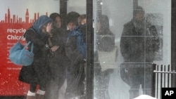 Commuters wait for their bus in blowing snow, Feb. 5, 2014, in Chicago, Illinois.