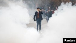 A man uses his phone during a demonstration outside the headquarters of the Democratic Party in Tirana, Albania, Jan. 8, 2022. 