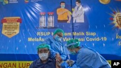 76-yer-old doctor Bachtiar Surya receives a shot of a COVID-19 vaccine from a colleague at Adam Malik Hospital in Medan, North Sumatra, Indonesia, Monday, Feb. 8, 2021.