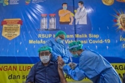 Dokter Bachtiar Surya (76 tahun), menerima suntikan vaksin COVID-19 dari seorang kolega di Rumah Sakit Adam Malik di Medan, Sumatera Utara, Senin, 8 Februari 2021. (AP)