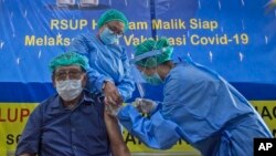 76-yer-old doctor Bachtiar Surya receives a shot of a COVID-19 vaccine from a colleague at Adam Malik Hospital in Medan, North Sumatra, Indonesia, Monday, Feb. 8, 2021.