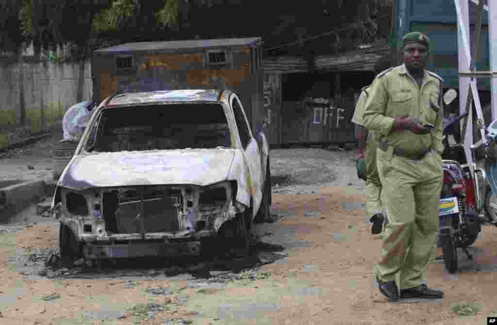 A prison guard walks near a burned out car, near to a prison in Bauchi, Nigeria, Thursday, Sept. 9, 2010, after the radical Muslim Boko Haram sect armed with assault rifles launched an attack at sunset on Tuesday Sept. 7, on the prison to free more than