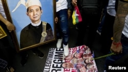 Tenaga kerja migran Myanmar menginjak poster anggota junta militer Myanmar saat protes menentang kudeta militer dan menuntut dikembalikannya demokrasi, di Bangkok, Thailand, 1 Mei 2022. (REUTERS/Soe Zeya Tun)