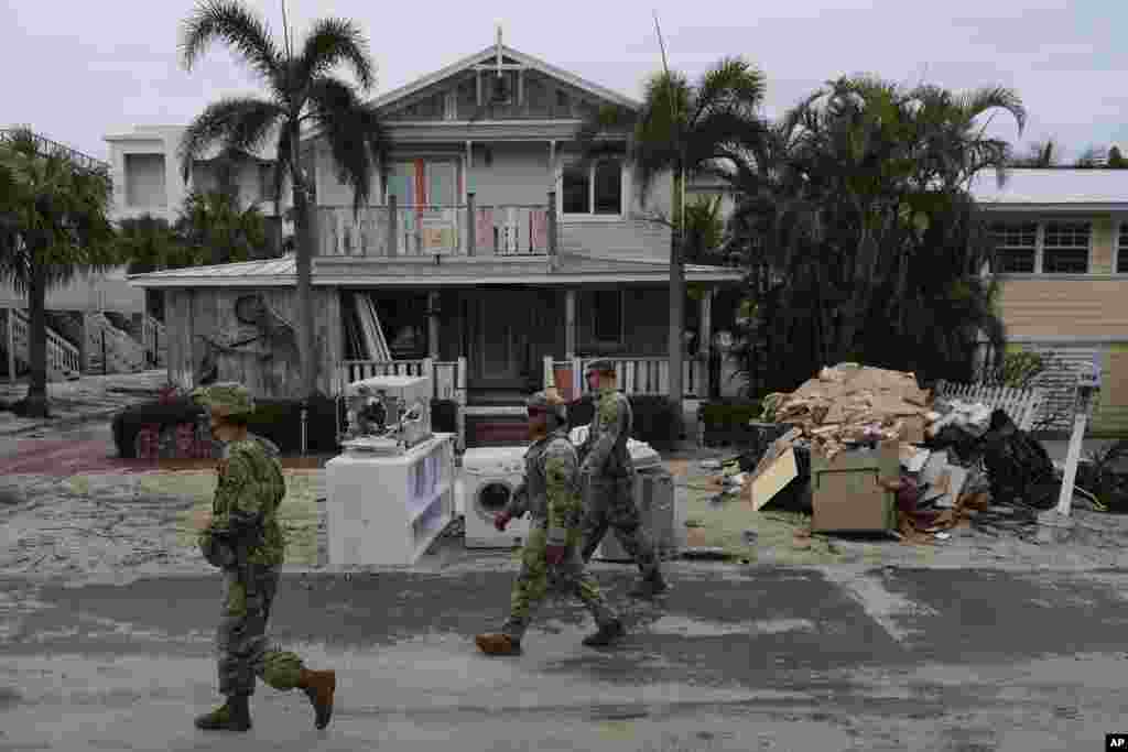 Members of the Florida Army National Guard check for any remaining residents in nearly-deserted Bradenton Beach, where piles of debris from Hurricane Helene flooding still sits outside damaged homes, ahead of the arrival of Hurricane Milton, Oct. 8, 2024, on Anna Maria Island.