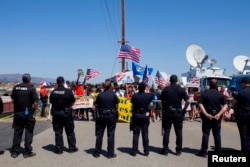 FILE - Demonstrators picket before the possible arrival of undocumented migrants who may be processed at the Murrieta Border Patrol Station in Murrieta, California, July 4, 2014.