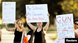 FILE - Angelina Lazo, center, an 18-year-old senior at Marjory Stoneman Douglas High School, who said she lost two friends in the shooting at her school, joins other gun control proponents with placards at a street corner in Coral Springs, Florida, Feb. 16, 2018.