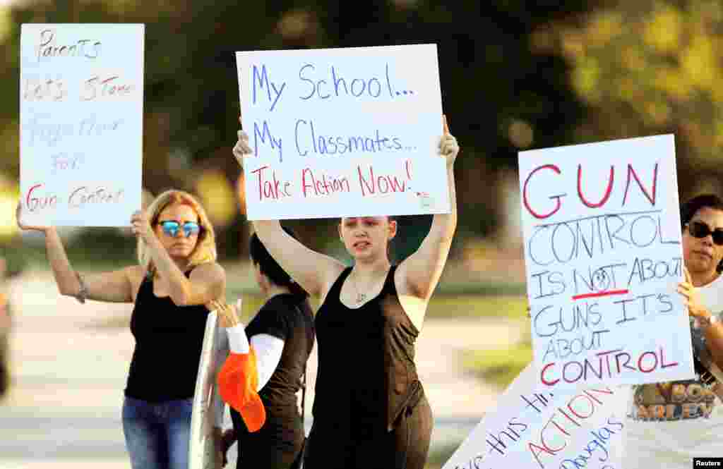 Angelina Lazo, center, an 18-year-old senior at Marjory Stoneman Douglas High School, who said she lost two friends in the shooting at her school two days ago, joins other gun control proponents with placards at a street corner in Coral Springs, Florida, 