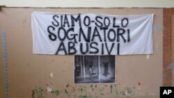 A banner reading "We are just unauthorized dreamers" is attached to the wall of the committee for “Le Vele di Scampia,” (the Sails of Scampia), a public housing project which for over a decade was the center for the Camorra Mafia syndicate's drug business, in Naples, southern Italy, Feb. 12, 2018. Whichever party can convert voters’ palpable anger in the south into support in Italy’s March 4 election could very well determine who governs Italy. A few dozen southern races, including in the Campania region embracing Naples, are critical. 