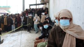 Afghans wait to receive food rations organized by the World Food Program (WFP) in Pul-e-Alam, the capital of Logar province, eastern of Afghanistan, Tuesday, Jan. 18, 2022.