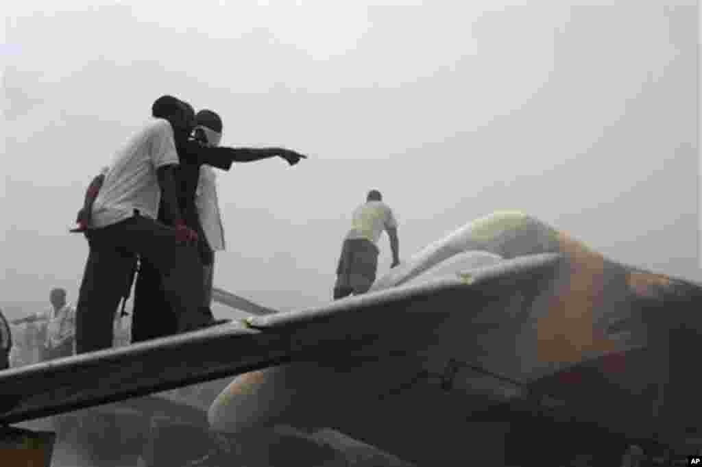 Onlookers stand on the tail wing of a crashed Dana Airlines passenger plane in a neighborhood just north of Murtala Muhammed International Airport, in Lagos, Nigeria, Sunday, June 3, 2012. The passenger plane carrying more than 150 people crashed in Niger