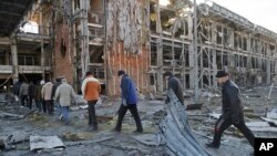 Ukrainian prisoners of war march to a truck after removing bodies of Ukrainian servicemen from the rubble of the airport building, seen in the background, outside Donetsk, Ukraine, Feb. 25, 2015.