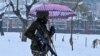 An Indian paramilitary trooper carries an umbrella as he walks through a park during snowfall in Srinagar.