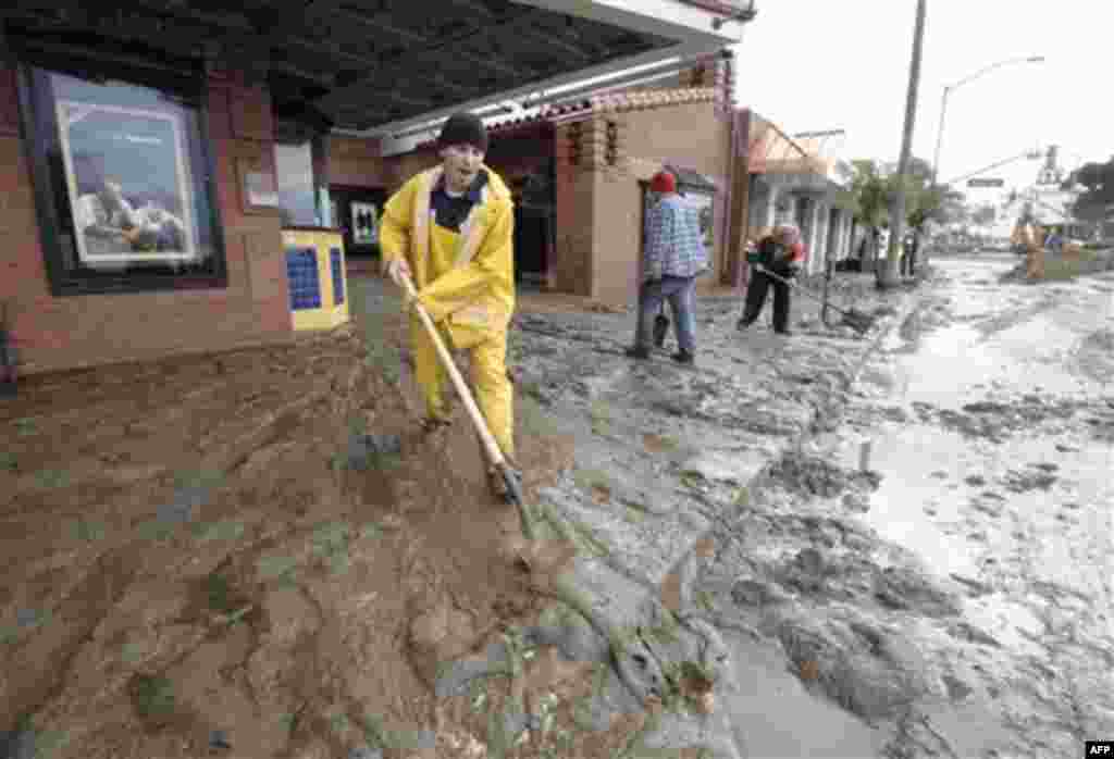 Rob Weller shovels mud out onto Pacific Coast Highway from the entrance to the Laguna Cinemas in Laguna Beach, Calif. Wednesday, Dec. 22, 2010. (AP Photo/Denis Poroy)