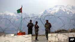 FILE - Afghan National Army soldiers stand guard at a checkpoint near the Bagram base in northern Kabul, Afghanistan, April 8, 2020.