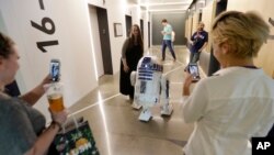 FILE - A life-size R2-D2 droid from the 'Star Wars' movie franchise mingles with workers at an Amazon.com building, May 4, 2017, in Seattle. 