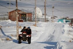 People ride through town on all-terrain vehicles, Jan. 18, 2020, in Toksook Bay, Alaska.