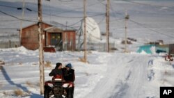 People ride through town on all-terrain vehicles, Jan. 18, 2020, in Toksook Bay, Alaska.