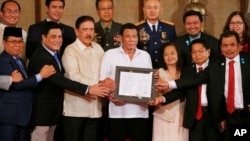 FILE - President Rodrigo Duterte, center, and leaders of the Moro Islamic Liberation Front, including Al Haj Murad Ebrahim, left, Mohagher Iqbal, right, and Ghadzali Jaafar, second from right, hold together the signed "Organic Law for the Bangsamoro Autonomous Region in Muslim Mindanao" during a presentation at Malacanang Palace in Manila, Philippines, Aug. 6, 2018.