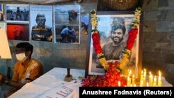 A man sits next to a memorial for Reuters journalist Danish Siddiqui after he was killed while covering a clash between Afghan security forces and Taliban fighters near a border crossing with Pakistan. (REUTERS/Anushree Fadnavis)